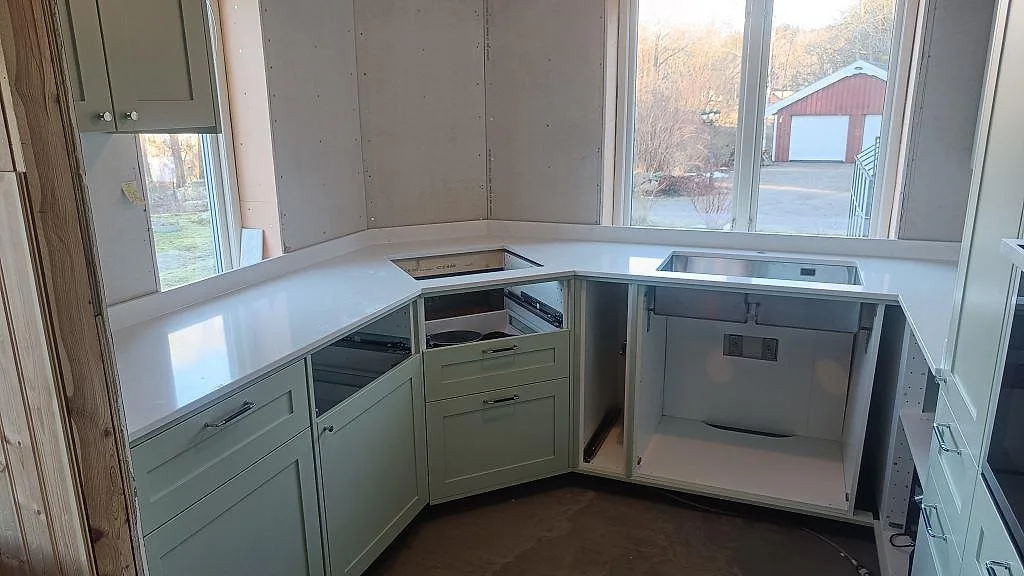 Köksbänkskiva i vit Silestone Eternal Statuario, polerad kvartskomposit, i ett U-format kök med grön inredning i Alingsås.