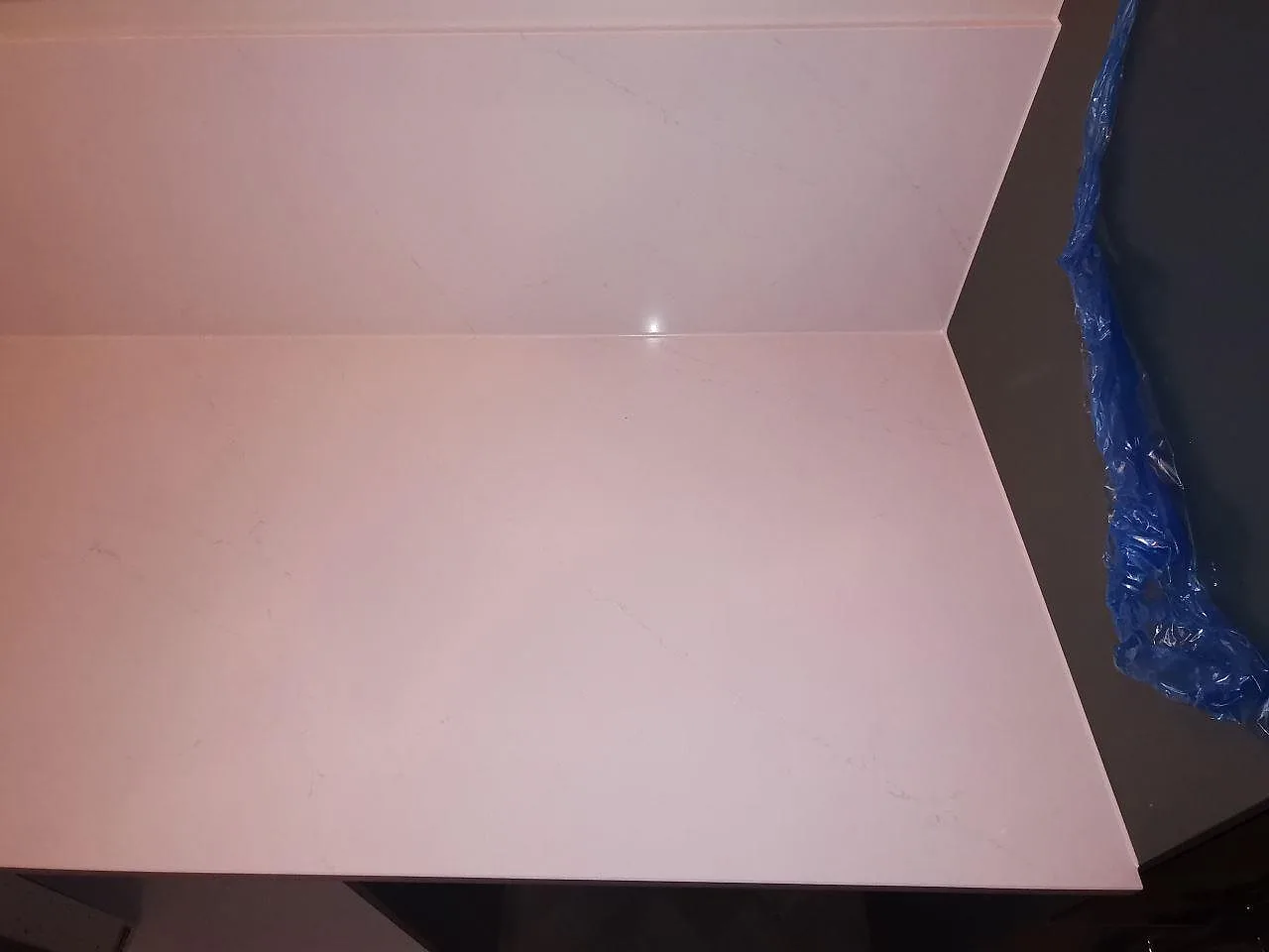 Etableringsbild av kök i Borås med vit köksbänkskiva i Silestone Eternal Statuario, blåa luckor och svart vägghängd fläkt, under montering.