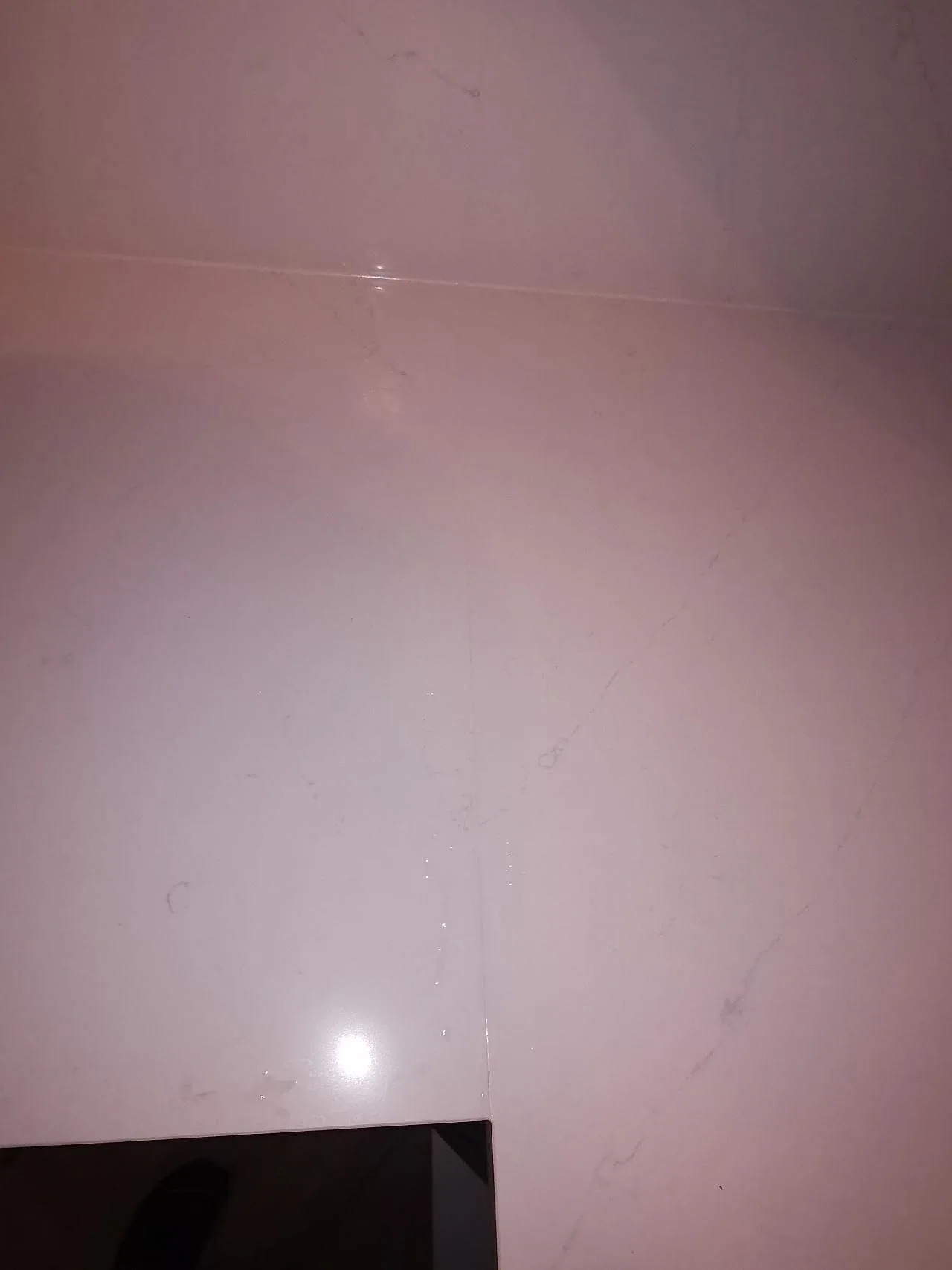 Polerat stänkskydd i Silestone Eternal Statuario med grå ådring och kontakthål i ett kök i Borås.