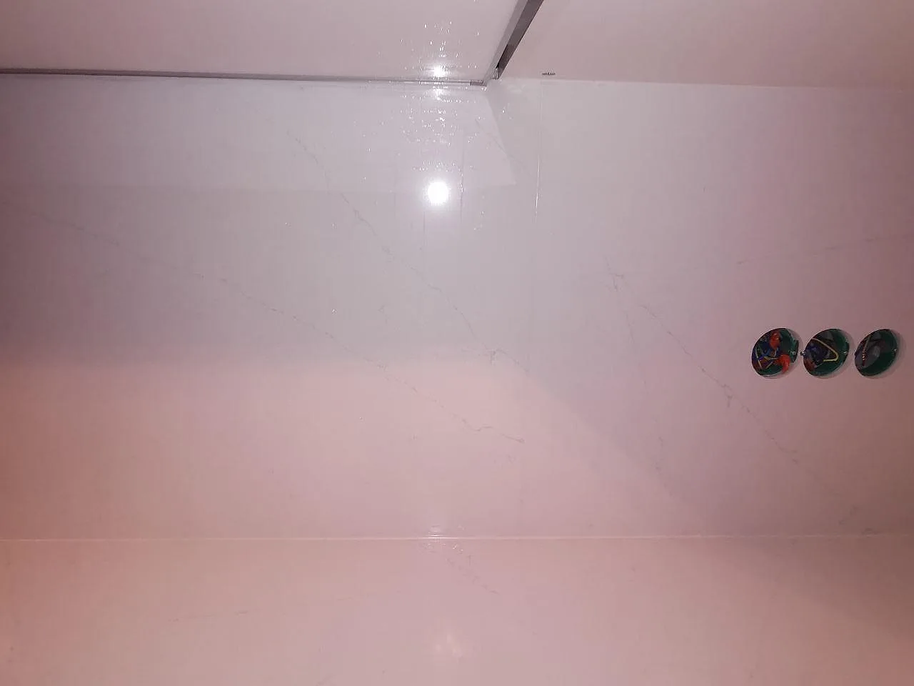 Detalj av polerat stänkskydd och köksbänkskiva i Silestone Eternal Statuario med grå ådring, i ett kök i Borås.