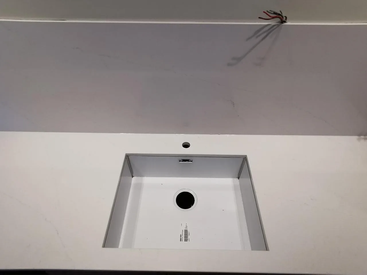 Underlimmad rostfri diskho i en polerad Silestone Eternal Statuario bänkskiva med stänkskydd i samma sten i ett kök i Borås.