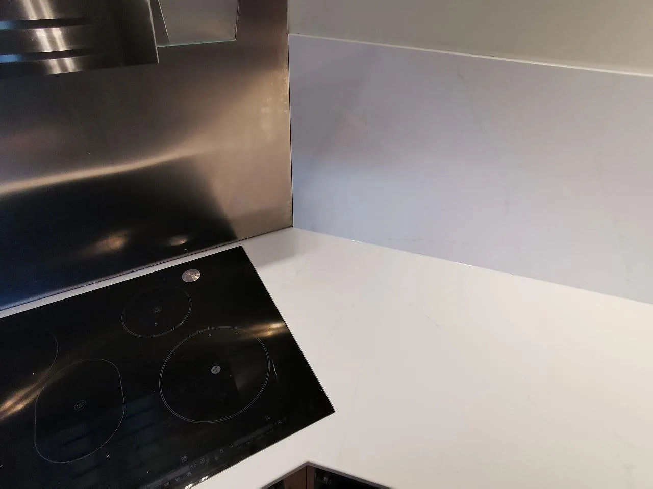 Polerad Silestone Eternal Statuario bänkskiva i hörnet av ett kök i Borås med övermonterad Siemens induktionshäll och uppvikt stänkskydd i samma sten.