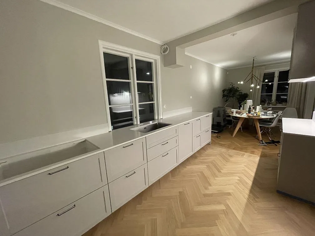 Polerad köksbänkskiva i Silestone Eternal Statuario med diskhoar, fönsterparti och uppvikt stänkkant längs väggen i Bromma.