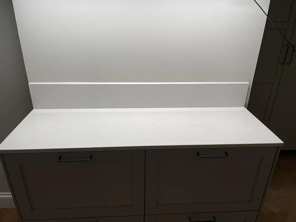 Närbild av vit Silestone Eternal Statuario som polerad bänkskiva och matchande stänkskydd på underskåp i Bromma.