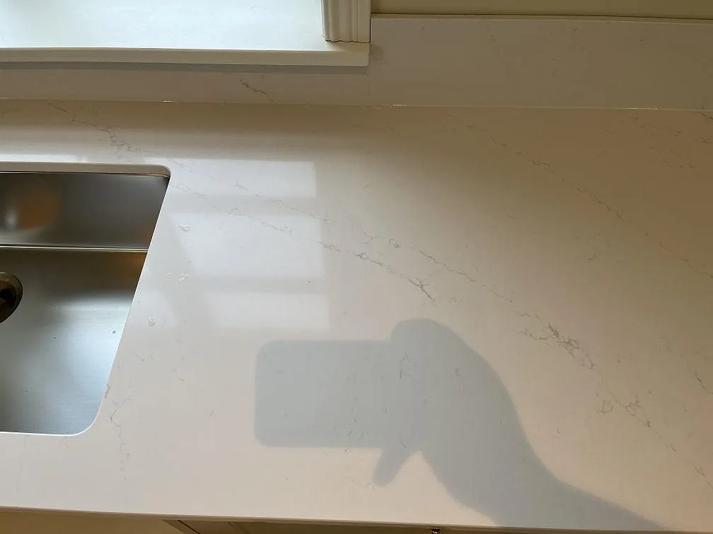 Polerad Silestone Eternal Statuario bänkskiva med underlimmad rostfri diskho vid fönstret i ett kök i Färjestaden.