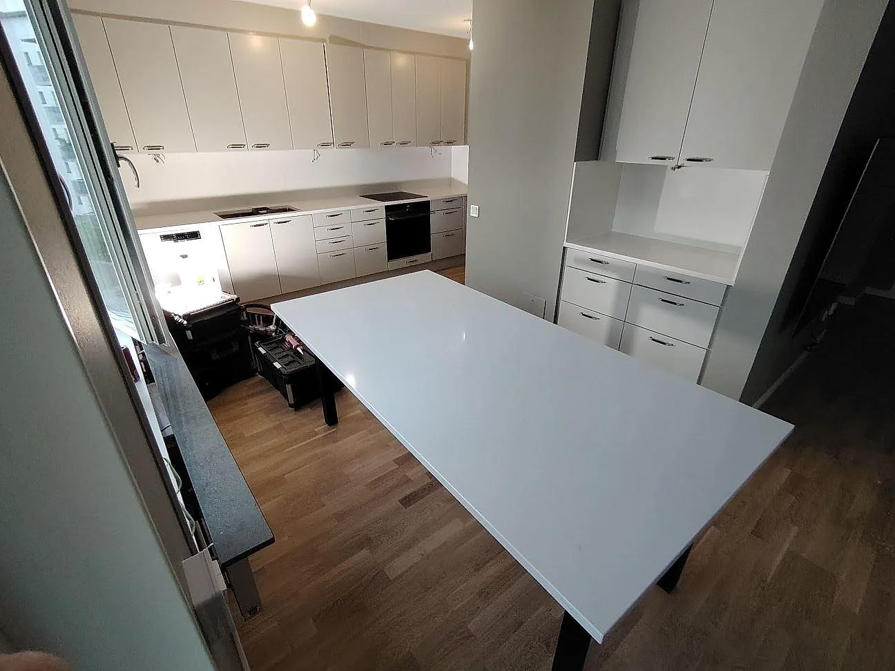 Stor polerad skivyta i Silestone Eternal Statuario komposit framför väggbänk och stänkskydd i ett kök under montering i Frösunda.