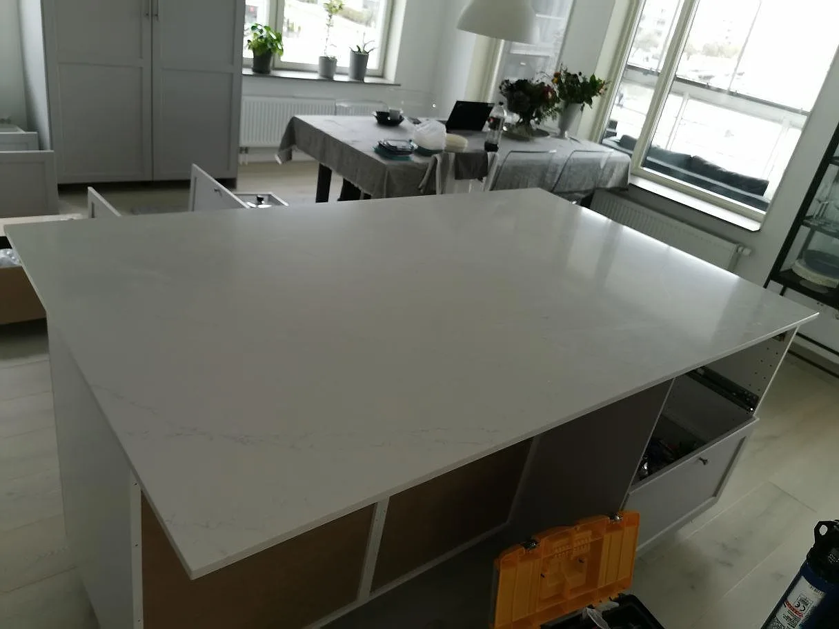 Köksö i vit Silestone Eternal Statuario med grå ådring och öppna hyllor, i en ljus lägenhet i Göteborg.