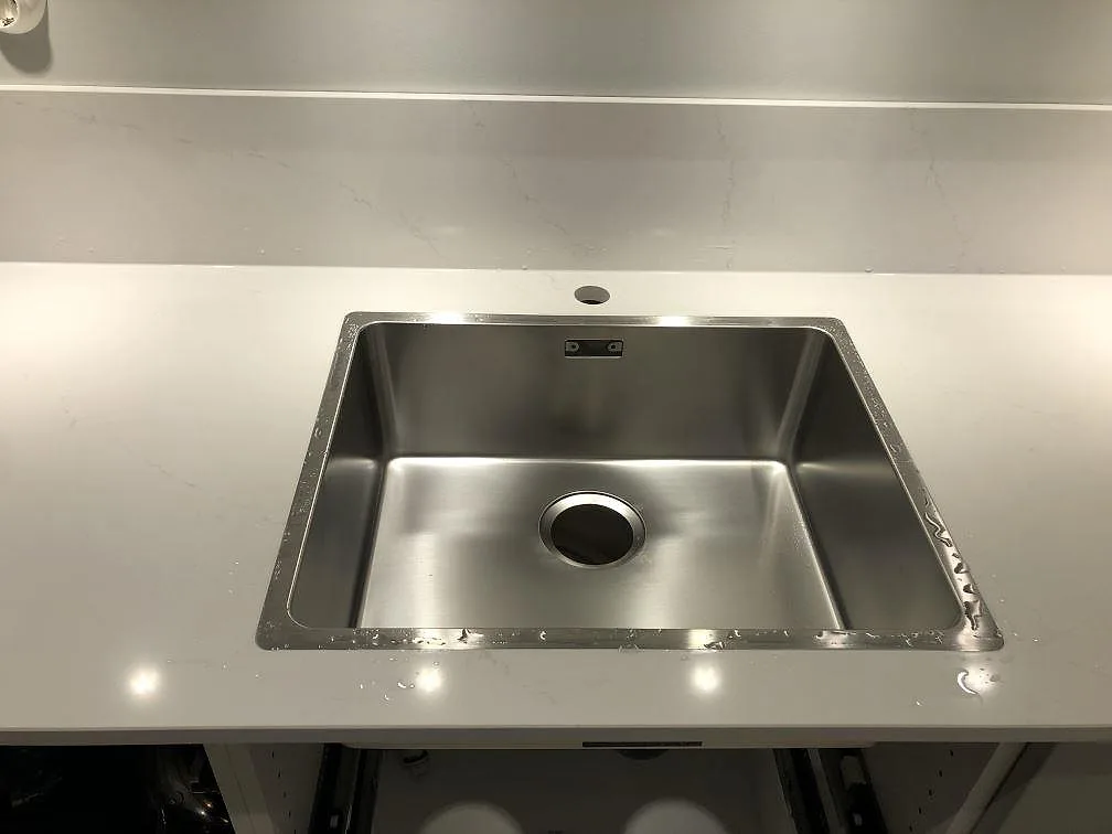 Underlimmad rostfri diskho i en polerad köksbänkskiva i Silestone Eternal Statuario i Göteborg.