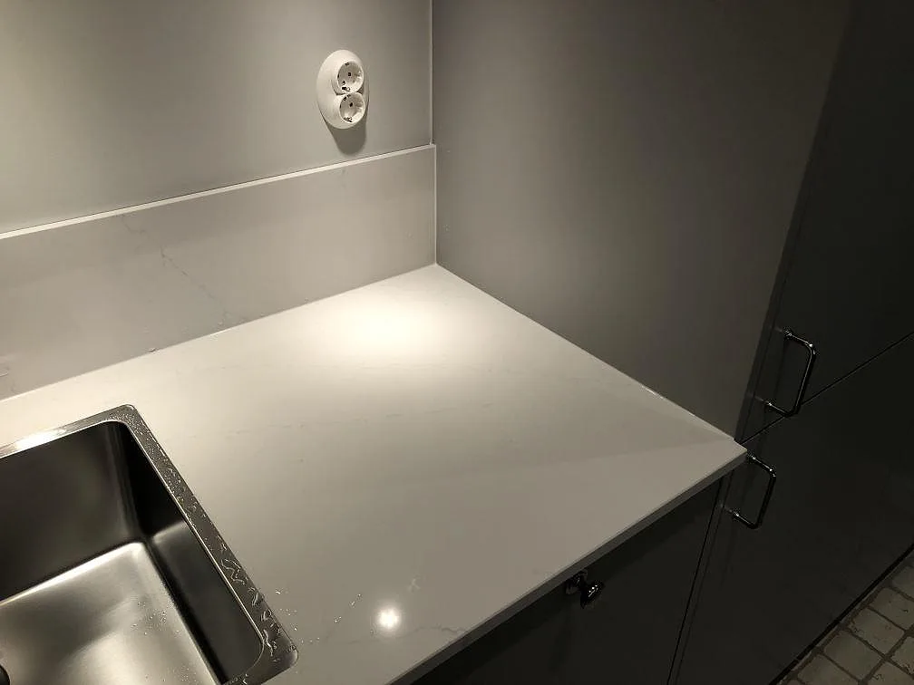 Polerad bänkskiva i Silestone Eternal Statuario med underlimmad rostfri diskho och uppvikt stänkkant i ett kök i Göteborg.