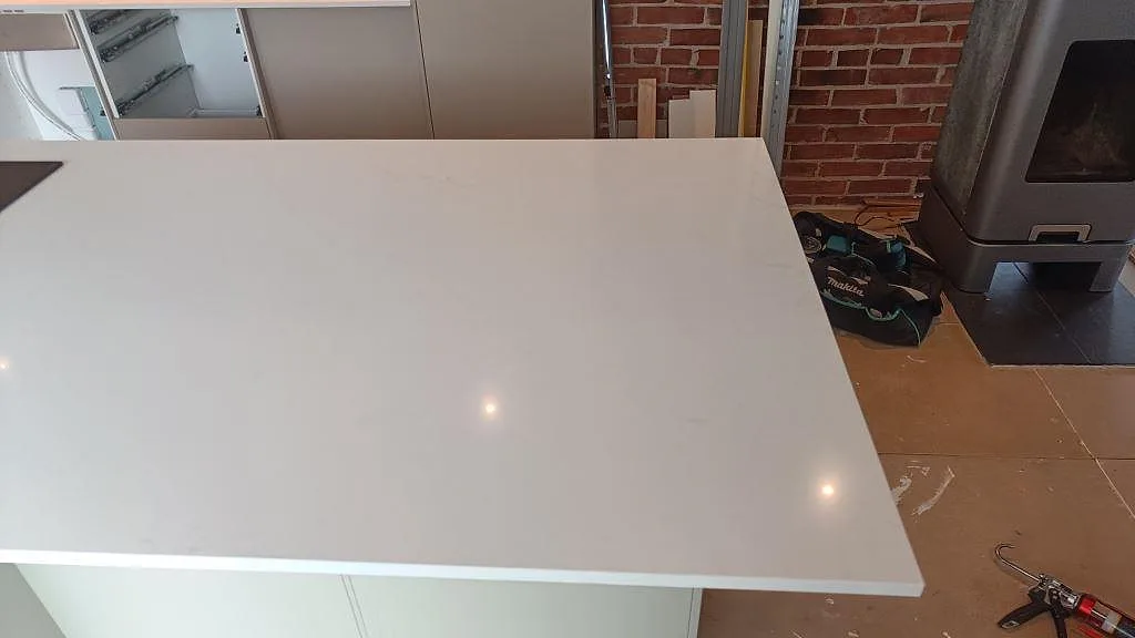 Blank vit Silestone Eternal Statuario som köksbänkskiva på köksö framför tegelvägg i ett kök i Halmstad.