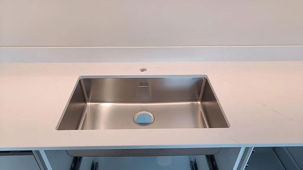 Underlimmad rostfri diskho monterad i polerad Silestone Eternal Statuario med stänkkant i köket i Halmstad.