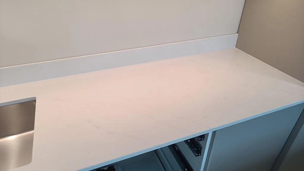 Ljus köksbänkskiva i Silestone Eternal Statuario, polerad, med stänkkant och synlig marmorerad ådring i Halmstad.