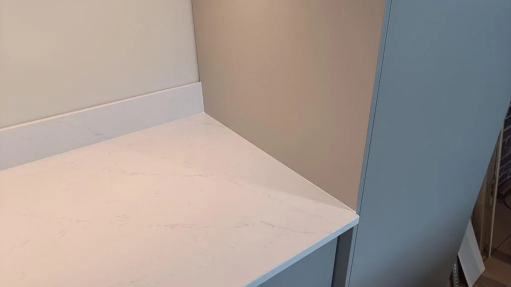 Detalj av polerad Silestone Eternal Statuario i kökshörn med matchande stänkkant och tunn grå ådring i Halmstad.