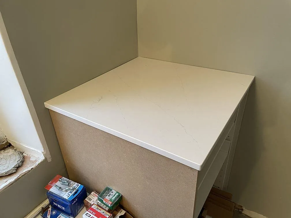 Hörnparti av köksbänkskiva i polerad Silestone Eternal Statuario monterad på stomme under installation i ett kök i Kävlinge.