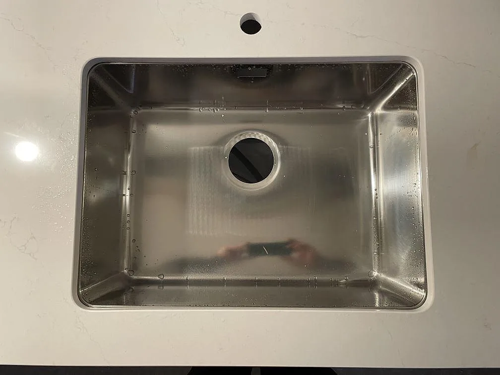 Detalj av underlimmad rostfri diskho infälld i vit Silestone Eternal Statuario med tydlig ådring i ett kök i Kävlinge.