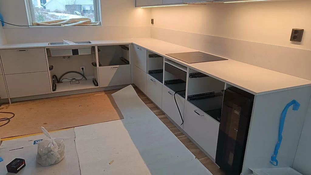 Köksbänkskiva i vit Silestone Eternal Statuario, polerad, i ett L-format kök med infälld induktionshäll i Karlshamn, fotograferat under montering.