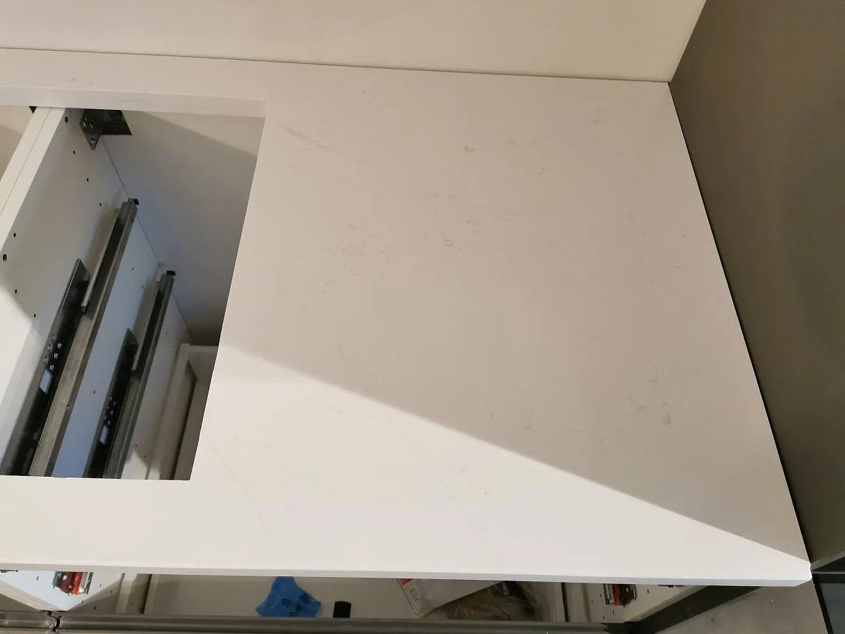 Polerad bänkskiva i Silestone Eternal Statuario med urtag för häll över öppna köksstommar i ett kök i Kristianstad.