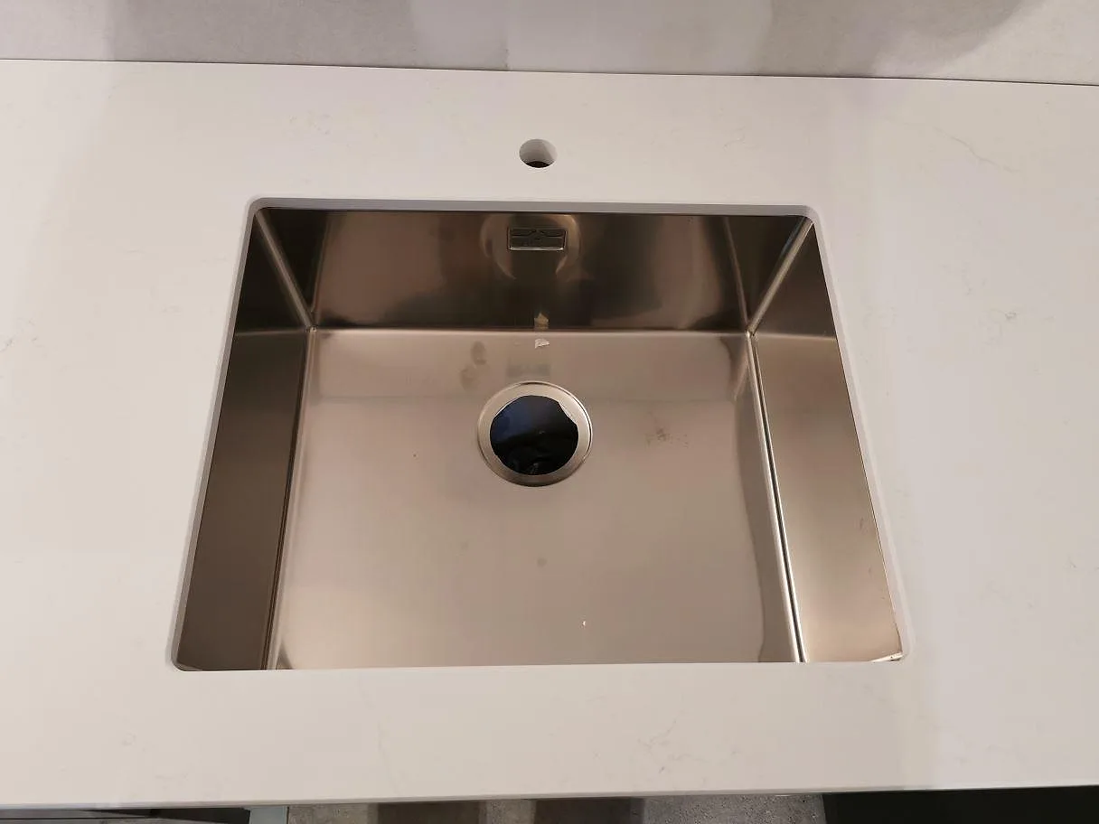 Underlimmad rostfri diskho i polerad vit Silestone Eternal Statuario med blandarehål i ett kök i Kristianstad.