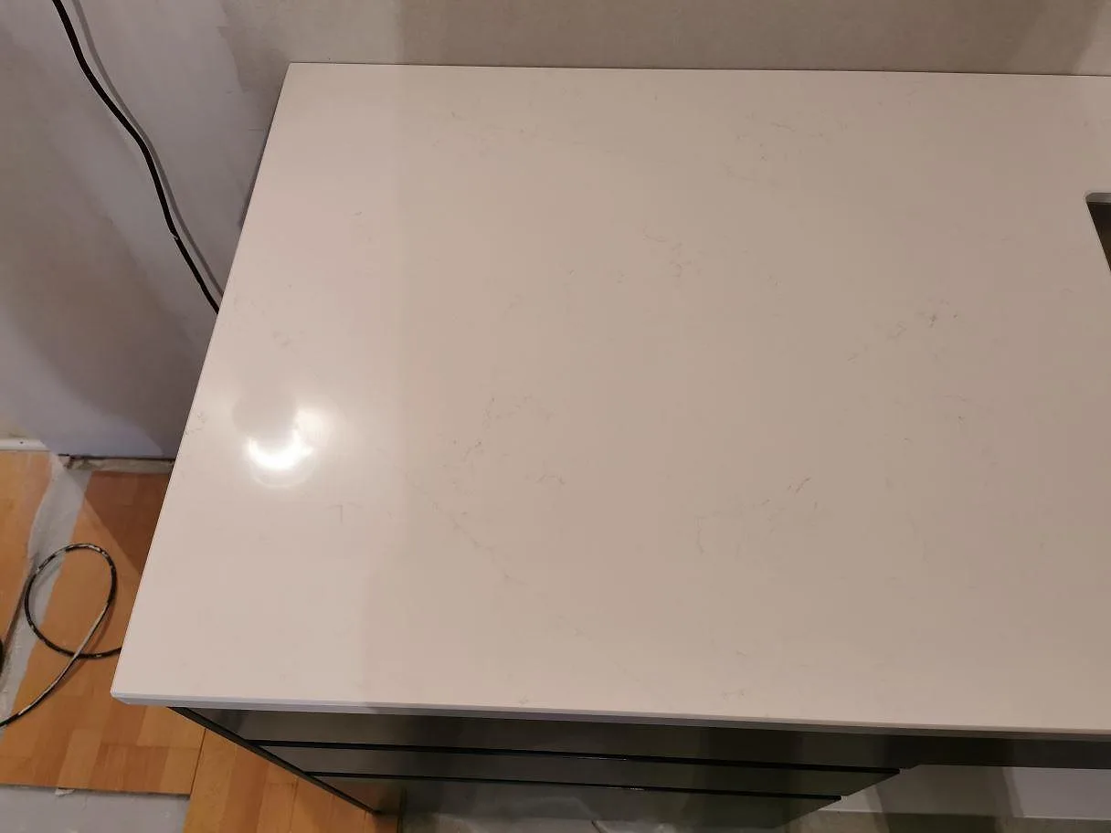 Polerad bänkskiva i vit Silestone Eternal Statuario med mjuk grå ådring i ett kök i Kristianstad.