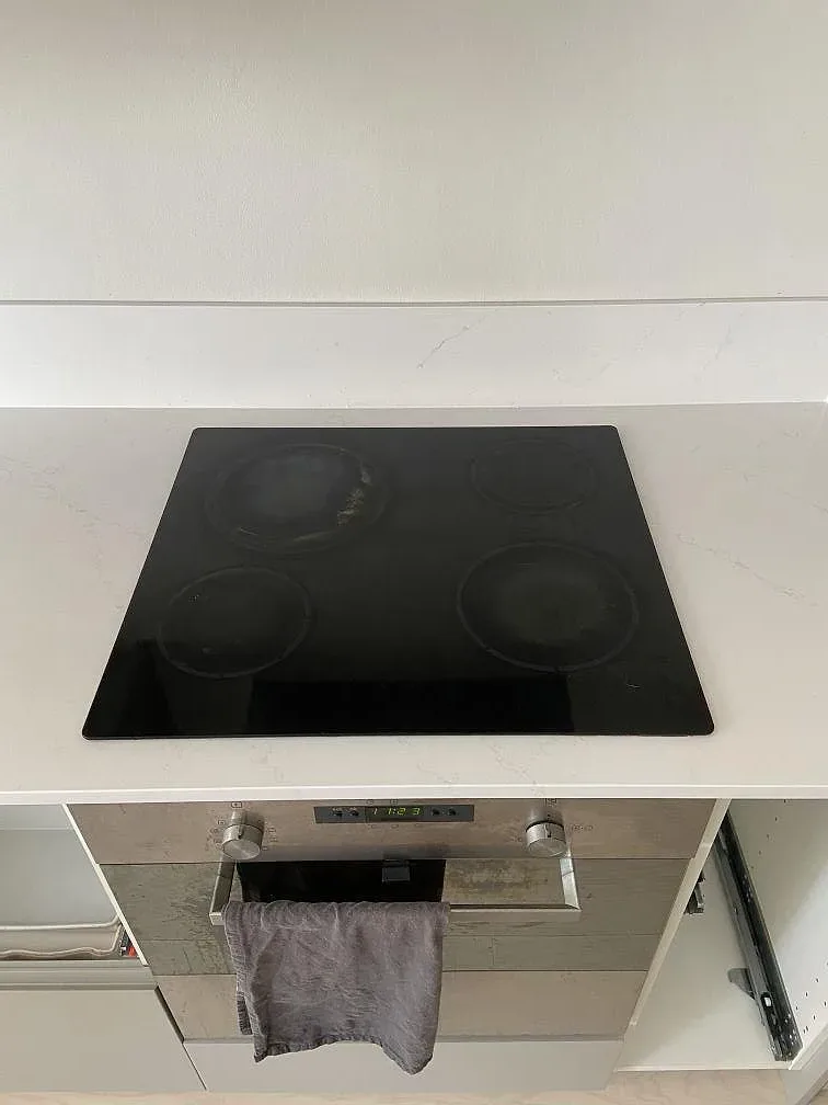 Svart induktionshäll infälld i vit Silestone Eternal Statuario bänkskiva i ett kök i Kungsbacka.