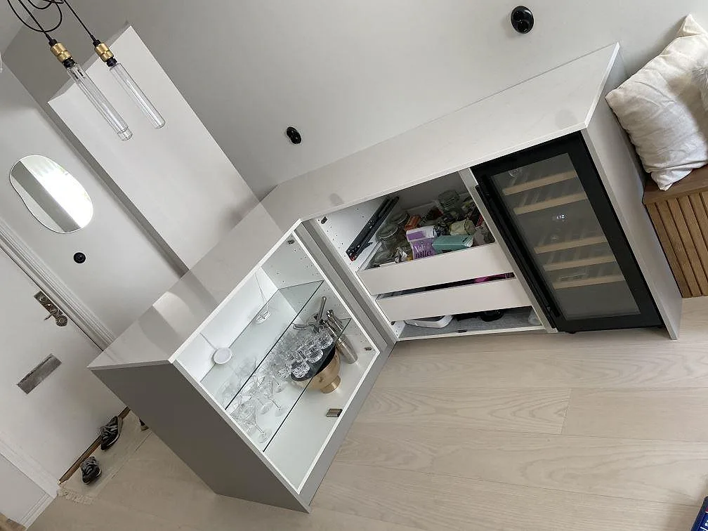 Köksö i vit Silestone Eternal Statuario med glasvitrinskåp och integrerad vinkyl i ett kök i Kungsbacka.