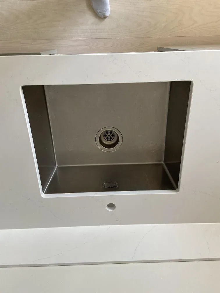 Underlimmad diskho i rostfritt stål i en polerad bänkskiva av Silestone Eternal Statuario i ett kök i Kungsbacka.