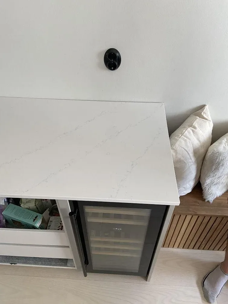Gerad sida på köksö i polerad Silestone Eternal Statuario intill en inbyggd vinkyl i ett kök i Kungsbacka.