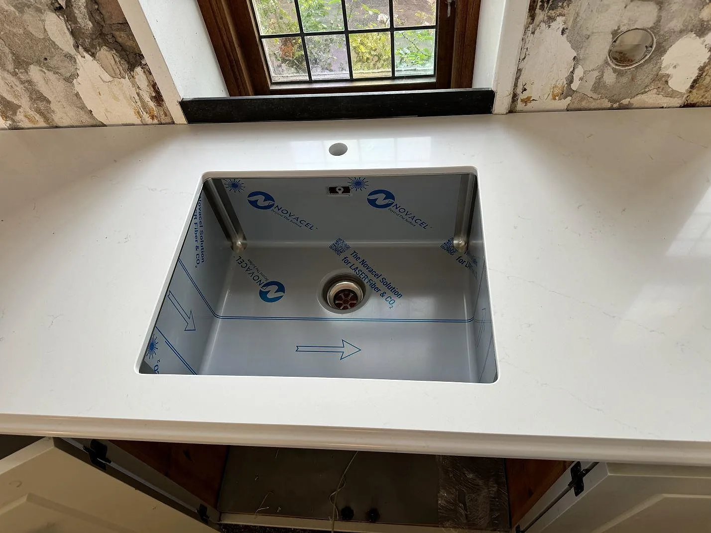 Polerad Silestone Eternal Statuario bänkskiva med diskho med skyddsfilm och svag grå ådring i ett kök i Limhamn.