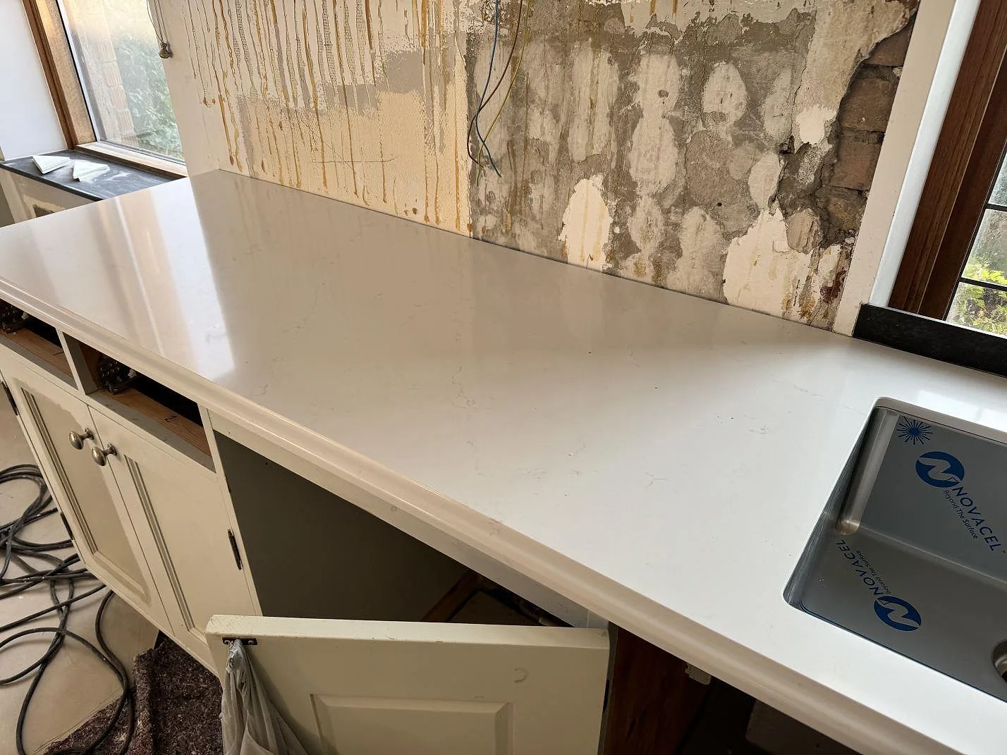 Närbild av polerad köksbänkskiva i Silestone Eternal Statuario med rak kant, ljus komposit och diskho vid fönster i Limhamn.