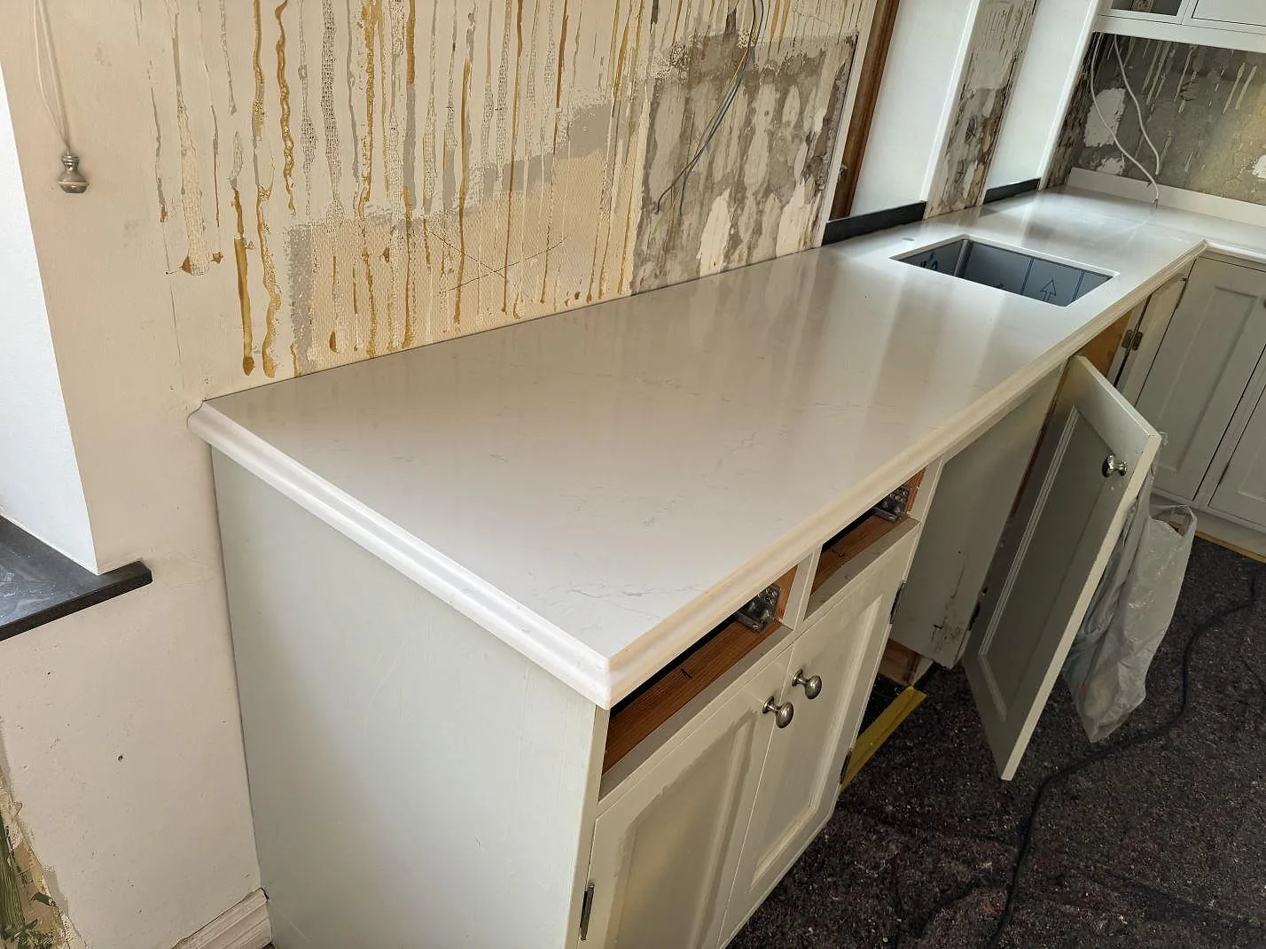 Lång polerad Silestone Eternal Statuario bänkskiva med ljus ådring och diskho med skyddsfilm i köket i Limhamn.