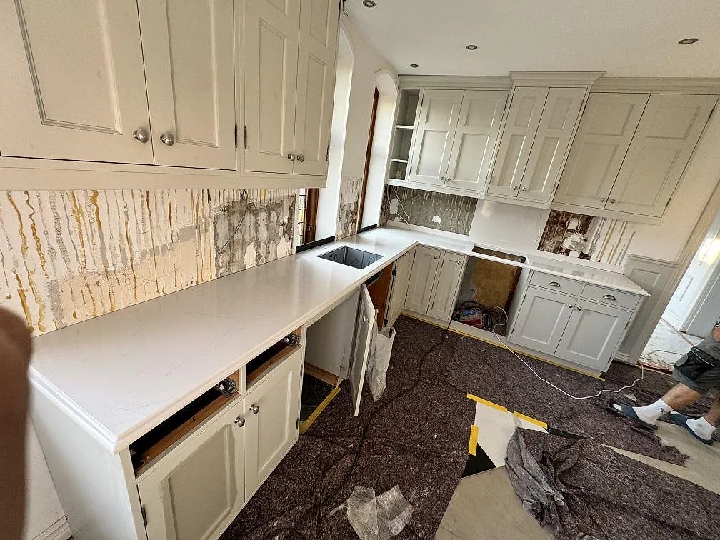 Polerad köksbänkskiva i vit Silestone Eternal Statuario, kvartskomposit, i ett U-format kök under montering i Limhamn.