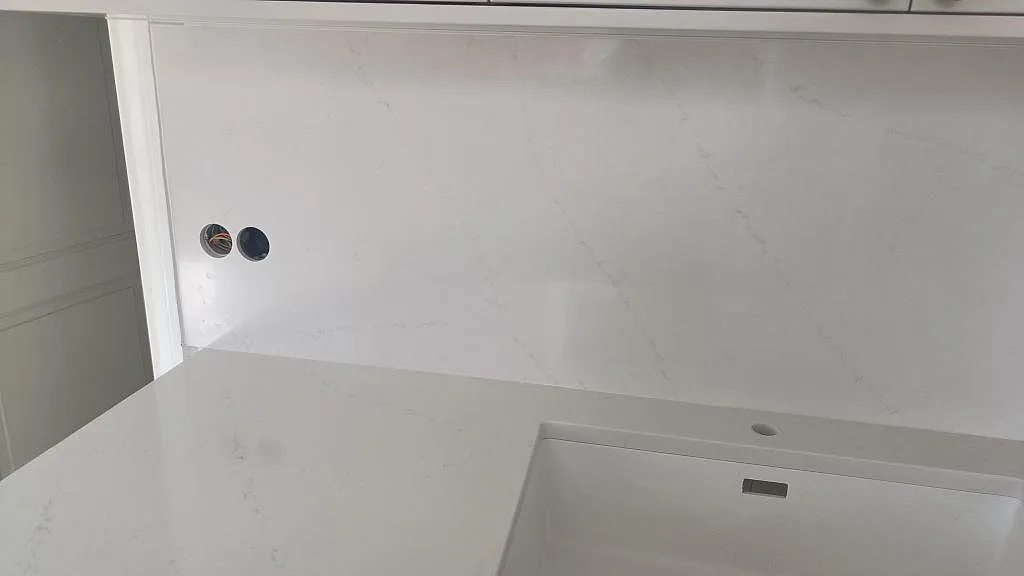 Närbild på vit Silestone Eternal Statuario, polerad, med diskho, väggskiva och grå ådring i kök i Limhamn.