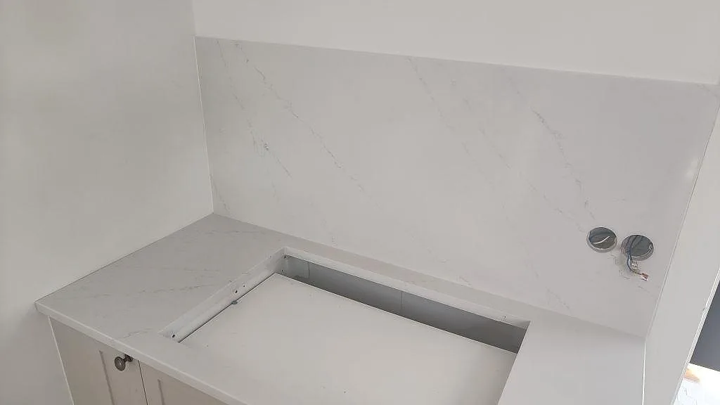 Detalj av hällöppning i vit Silestone Eternal Statuario, polerad, med marmorliknande ådring i kök i Limhamn.