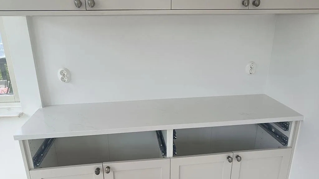 Rak köksbänkskiva i polerad Silestone Eternal Statuario på vita stommar i ett kök under montering i Limhamn.