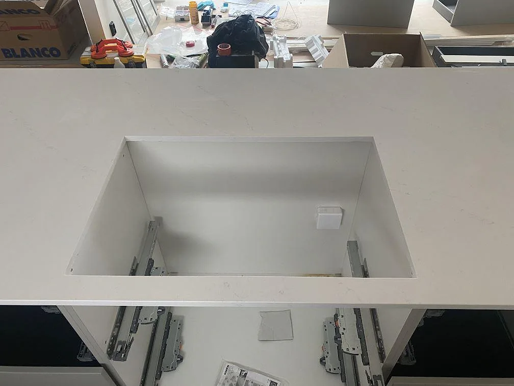 Silestone Eternal Statuario köksbänkskiva med stort diskhourtag och ljus grå ådring under montering i Ljungby.