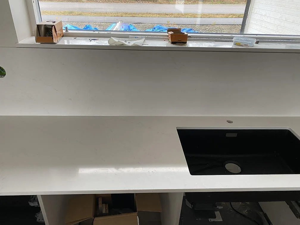 Köksbänkskiva i vit Silestone Eternal Statuario, polerad, med svart diskho och matchande stänkskydd vid fönster i Ljungby.