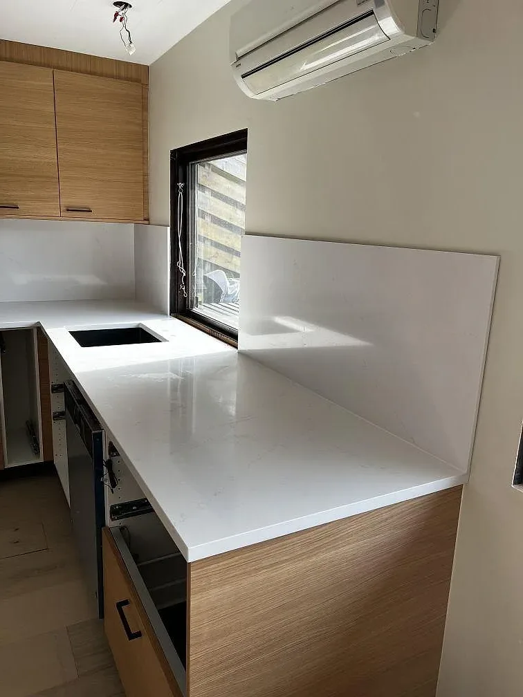 Vit Silestone Eternal Statuario köksbänk med uppvikt stänkkant under fönstret i ett kök under montering i Löddeköpinge.