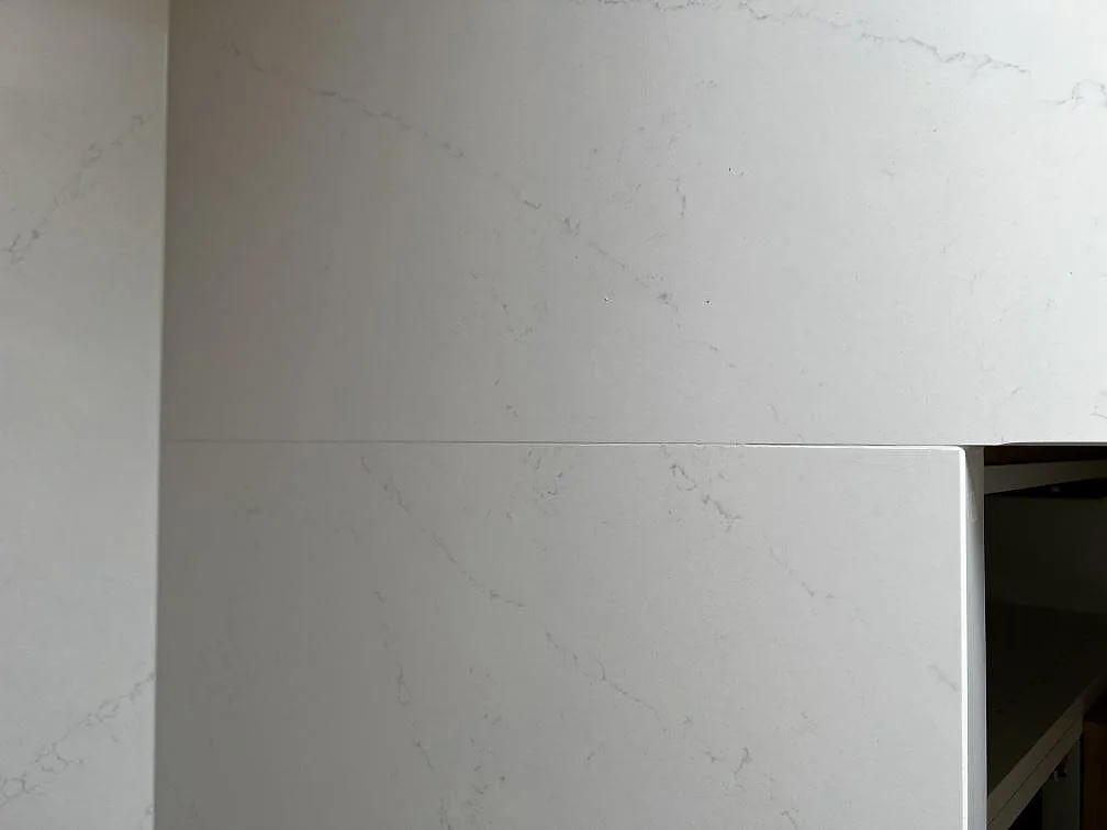 Polerad vit Silestone Eternal Statuario köksbänk med mjuk grå ådring och uppvikt stänkkant i hörnet i Löddeköpinge.