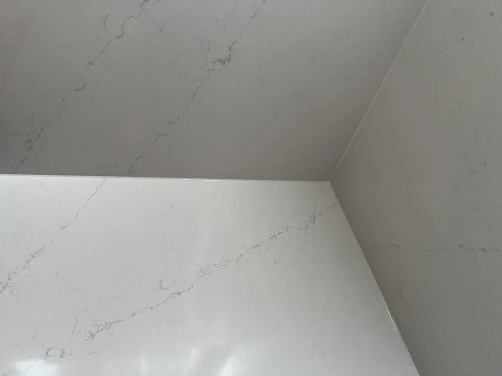 Närbild på den grå Calacatta-lika ådringen i polerad vit Silestone Eternal Statuario med uppvikt stänkkant i ett kök i Löddeköpinge.