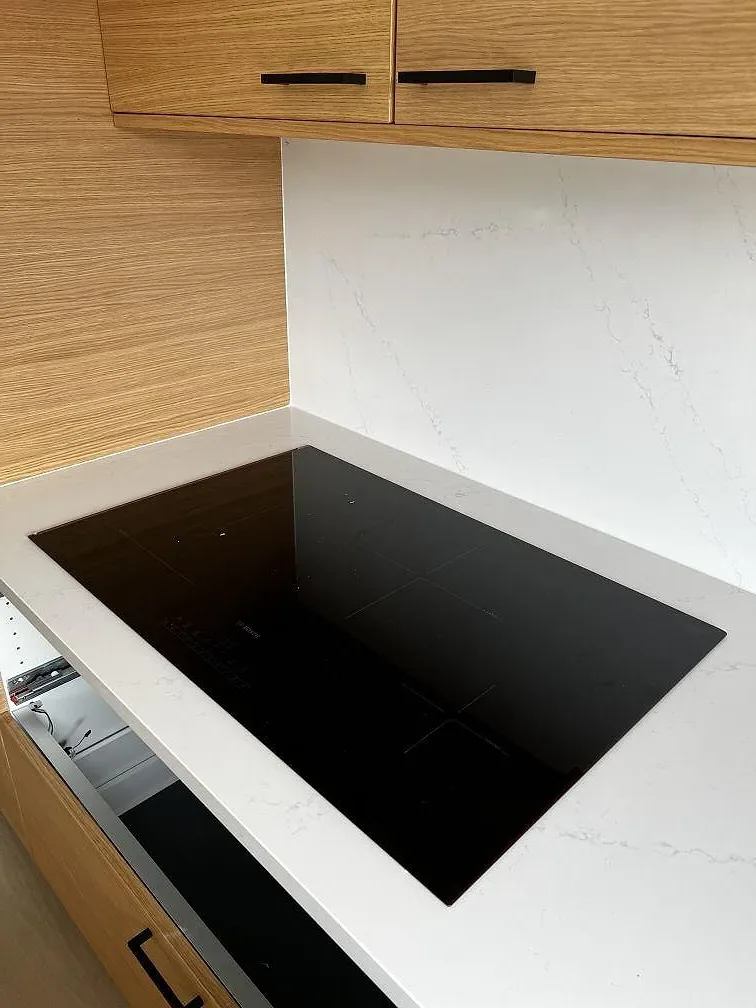 Plant infälld svart induktionshäll i polerad vit Silestone Eternal Statuario köksbänkskiva med ekluckor i Löddeköpinge.