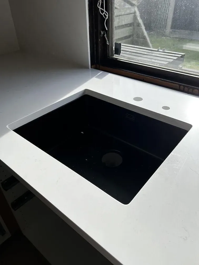 Underlimmad svart diskho i en polerad vit Silestone Eternal Statuario bänkskiva vid köksfönstret i Löddeköpinge.