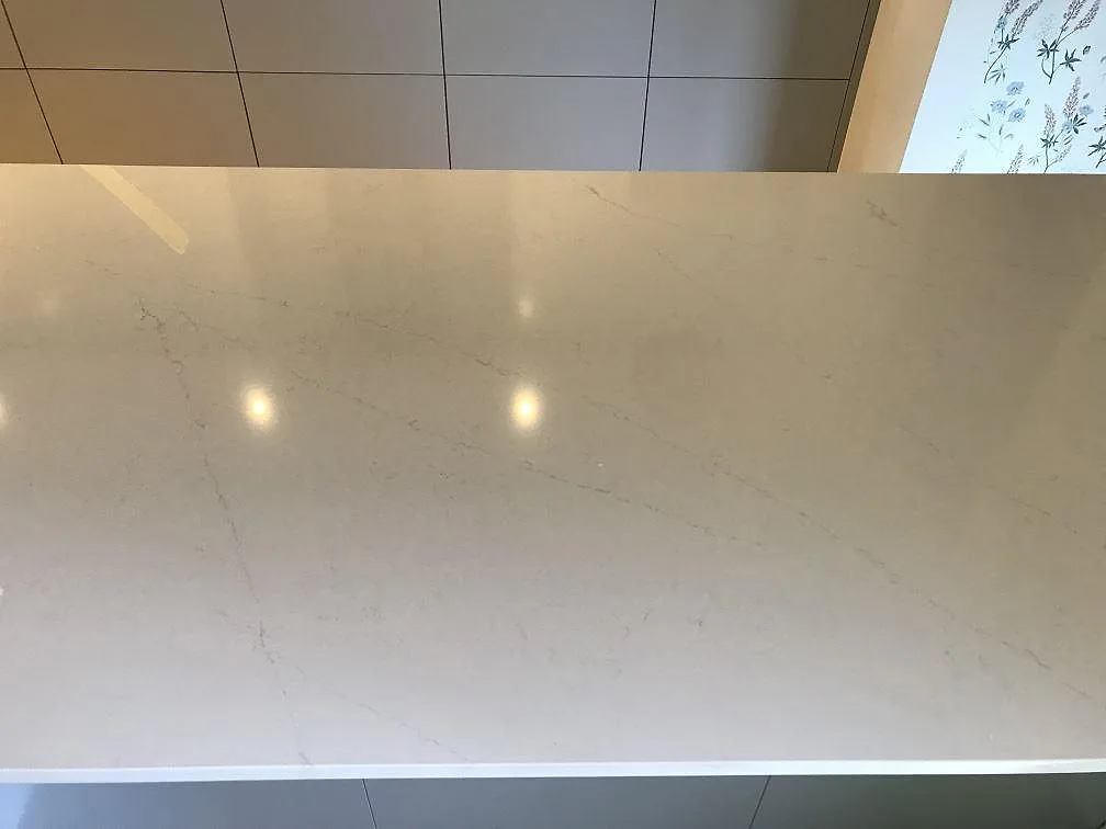Polerad vit köksbänkskiva i Silestone Eternal Statuario med fin grå Statuario-ådring och infälld belysning som speglas i ytan, i ett kök i Lomma.