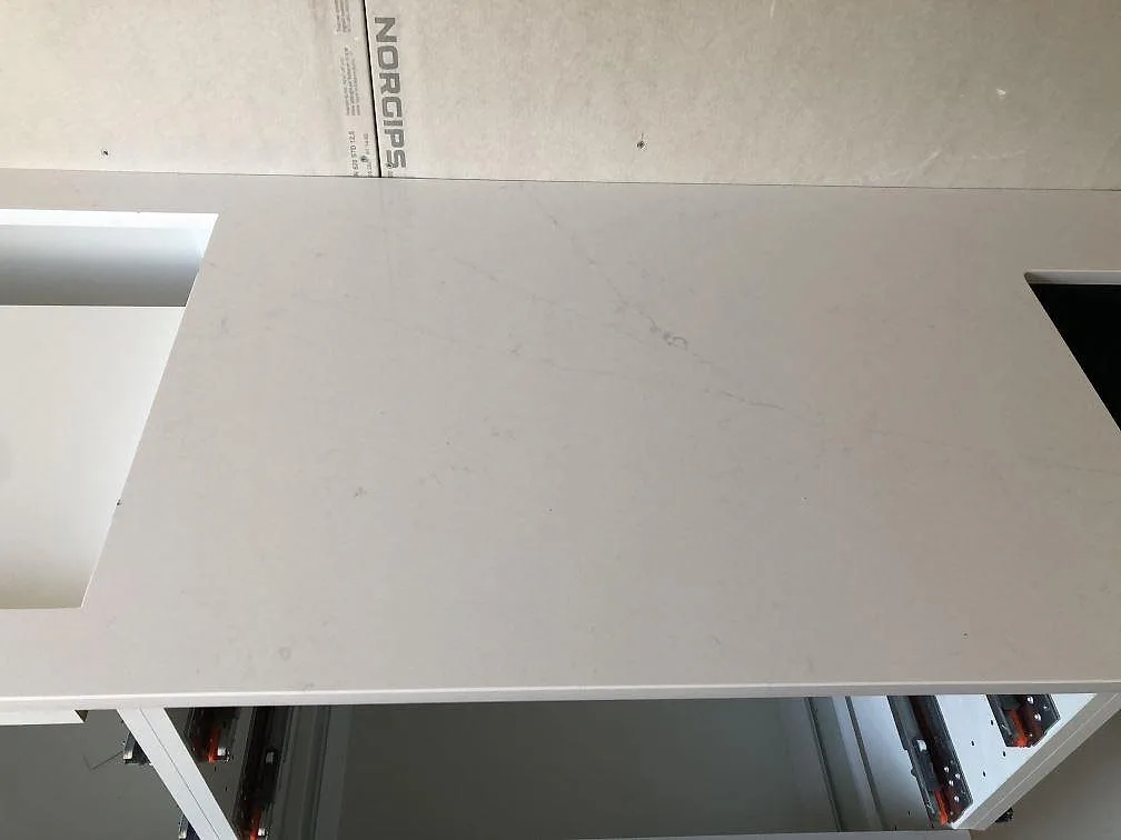 Ovanifrån av vit polerad Silestone Eternal Statuario köksbänkskiva med urtag mot omålad gipsvägg i ett kök i Malmö.