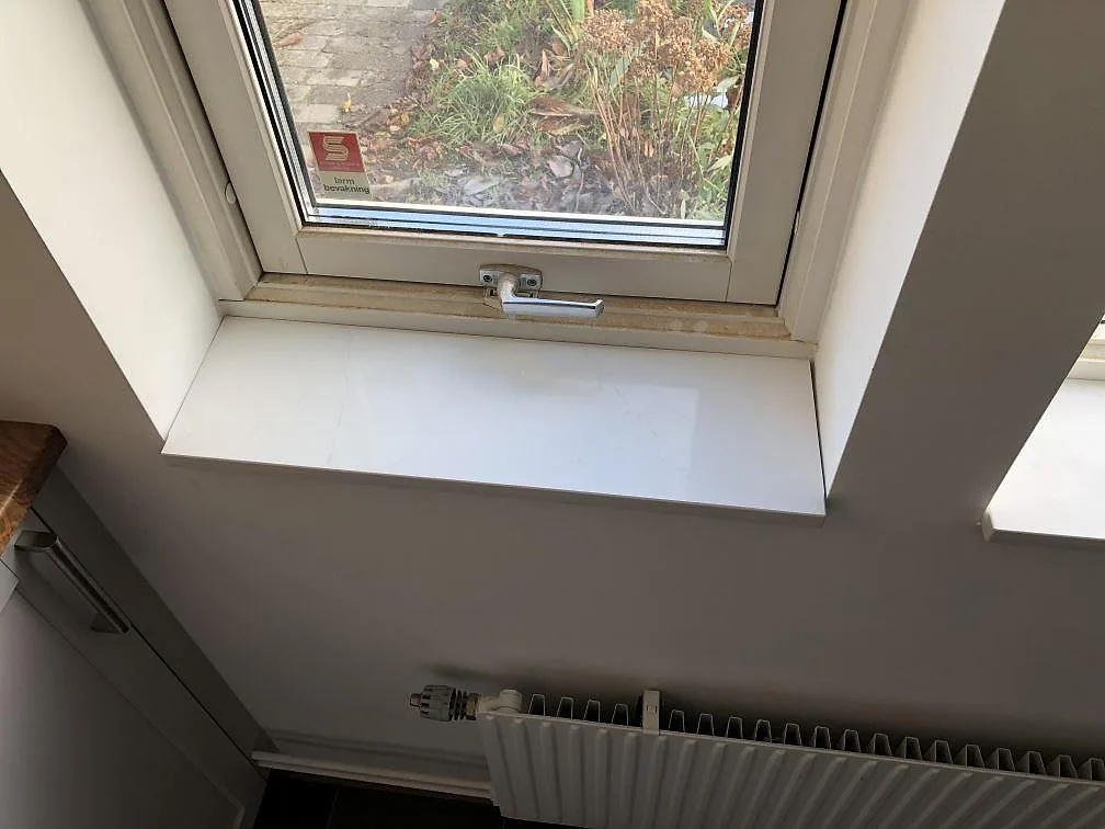 Fönsterbänk i vit polerad Silestone Eternal Statuario ovanför en radiator i ett kök i Malmö.