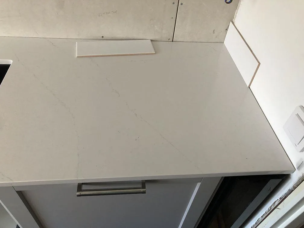 Polerad bänkskiva i vit Silestone Eternal Statuario med diskret grå ådring monterad på köksstommar i ett kök i Malmö under montering.