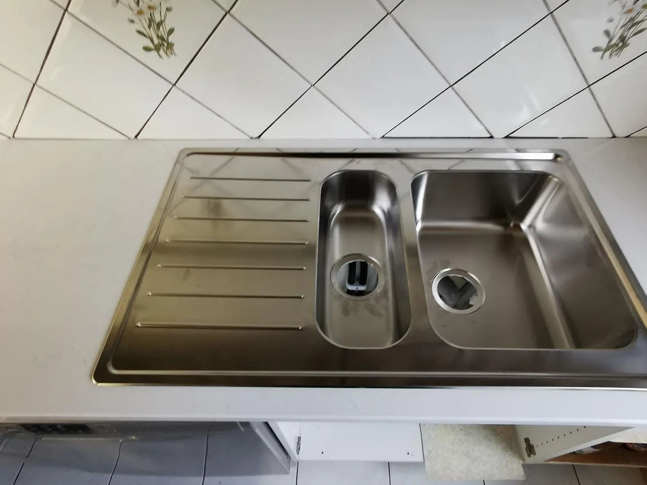 Övermonterad rostfri diskho med 1,5 hoar och avrinningsdel i en polerad bänkskiva av Silestone Eternal Statuario i Malmö.