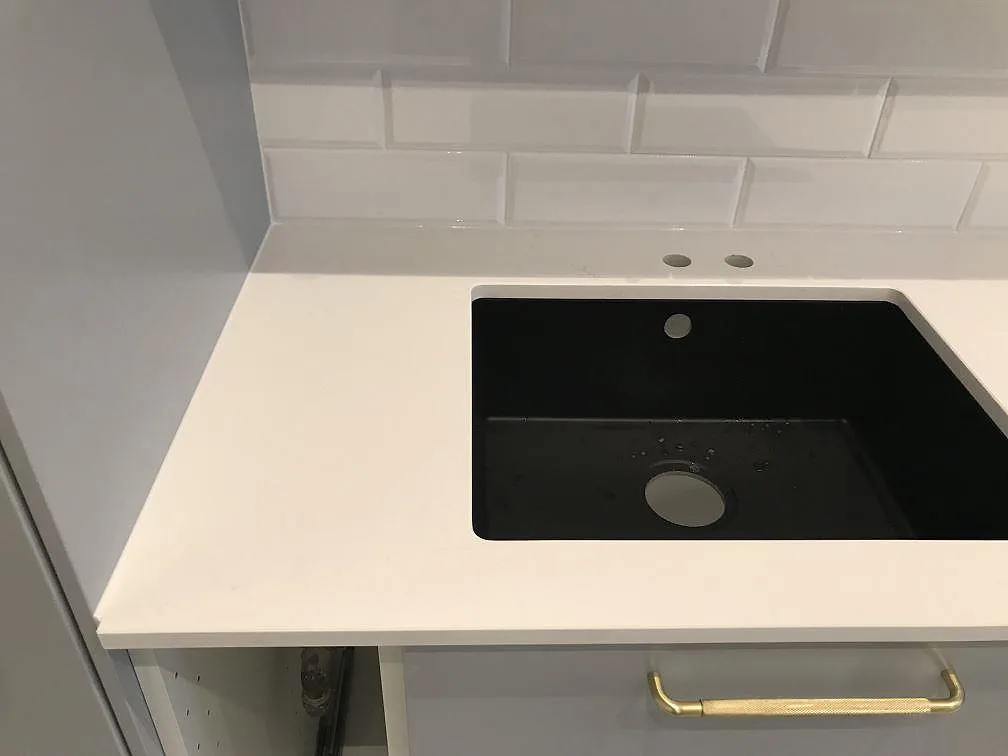 Svart underlimmad kompositdiskho i en köksbänkskiva av polerad Silestone Eternal Statuario i Malmö.