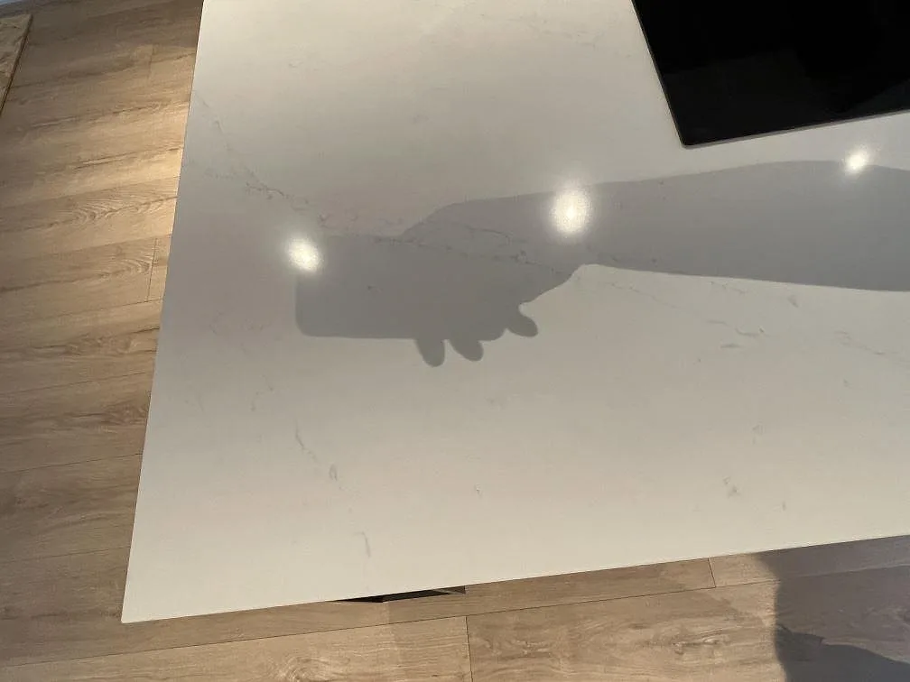 Ytnära bild av vit Silestone Eternal Statuario köksö med polerad finish, grå ådring och häll i Rönninge.