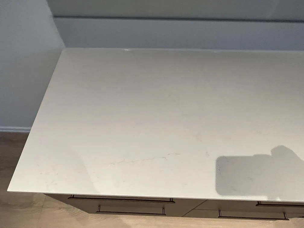 Rak köksbänkskiva i polerad Silestone Eternal Statuario med låg stänkkant mot väggen i ett kök i Rönninge.