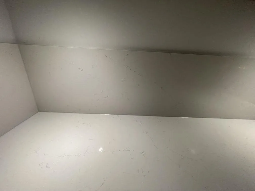 Polerad köksbänkskiva i vit Silestone Eternal Statuario med stänkskydd och fina grå ådror i ett kök i Stockholm.